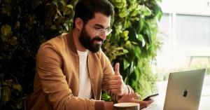 Man working on laptop giving thumbs up