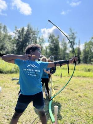 a young person holds a bow and arrow 