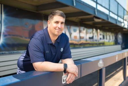 a man in a blue shirt stands in a baseball dugout 